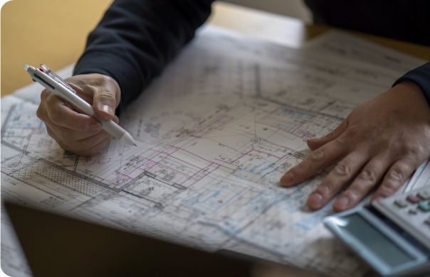設計図を広げ、ペンで検討する手元と電卓