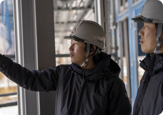 工事現場で作業員が指をさして説明している様子。