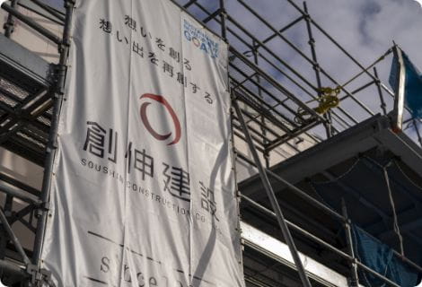 創伸建設のロゴと社名、SDGsロゴが入った建設現場の白い垂れ幕。